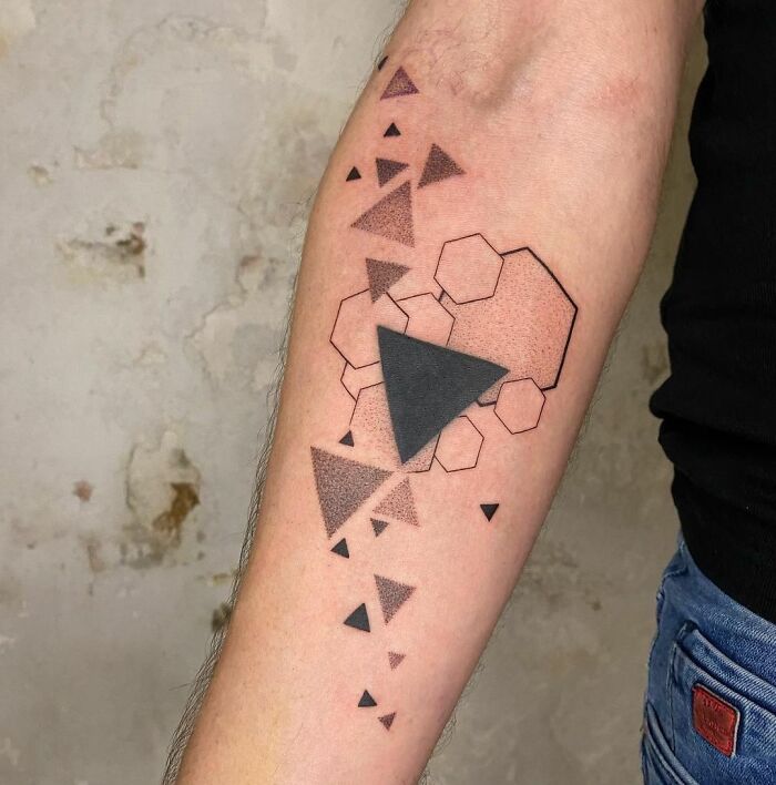Arm with geometric tattoo, featuring triangles and hexagons, showcasing a creative design idea.