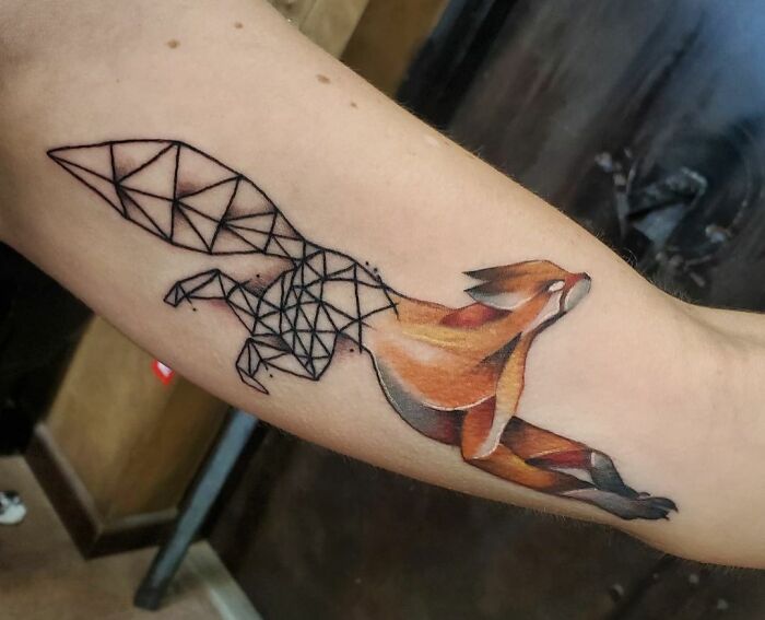 Geometric tattoo of a fox blending abstract shapes with vivid colors on an arm, showcasing creativity in design.