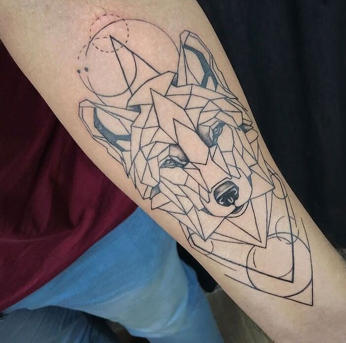 Geometric tattoo of a wolf on forearm featuring intricate lines and patterns.