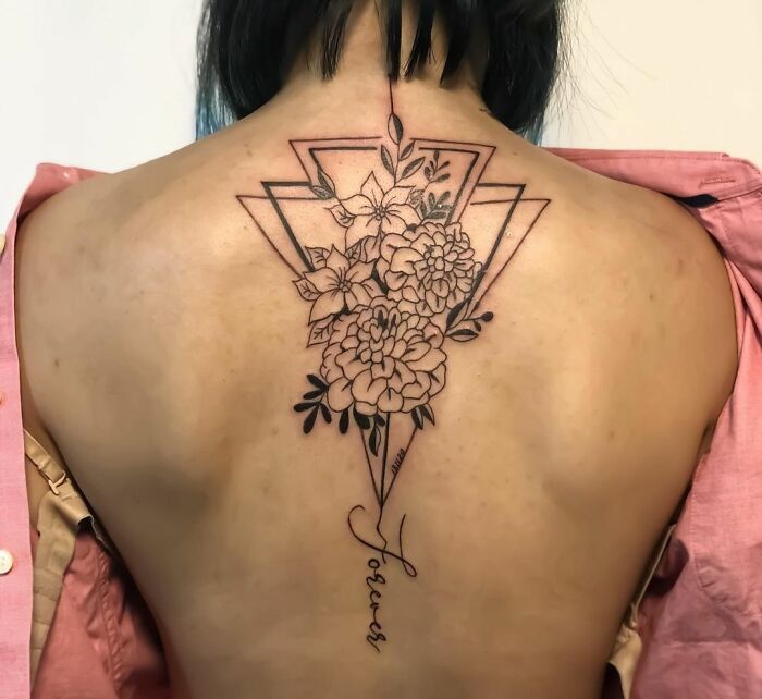 Geometric tattoo with floral and triangular patterns on a person's back.
