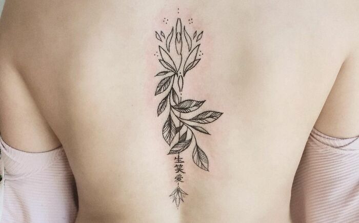 Geometric tattoo design on a person's back, featuring intricate leaves and shapes.