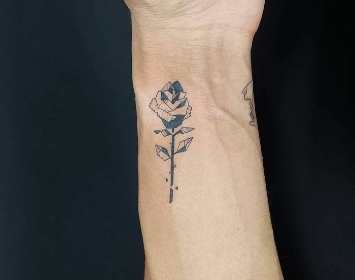 Geometric tattoo design on wrist, featuring a creative stylized rose with shapes and forms.
