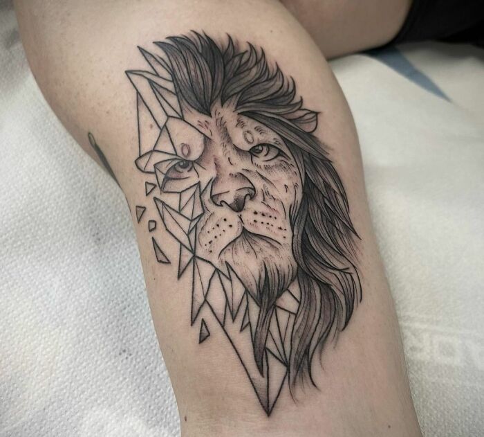 Geometric tattoo design of a lion with abstract shapes and forms, showcasing creativity on a person's leg.