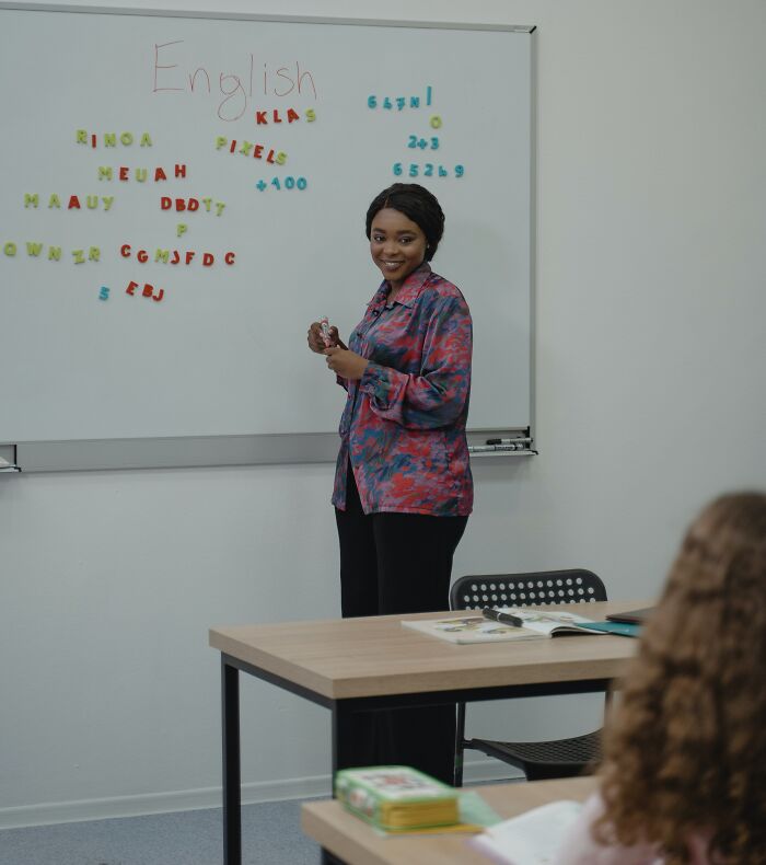 Teacher Teaching Students While Writing On Board 