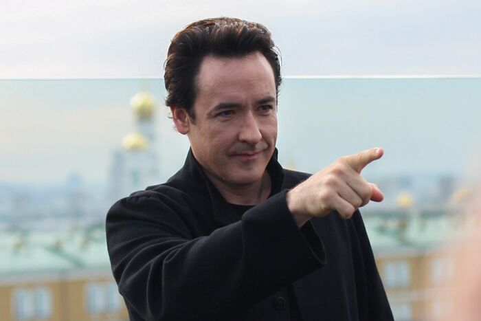 John Cusack pointing finger outdoors, representing celebrities who never married yet still found love.