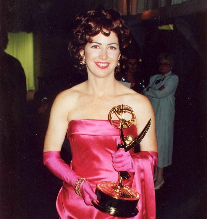 Dana Delany in a pink dress holding an Emmy, representing celebrities who never married yet found love.