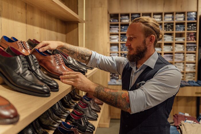 Man organizing shoes on a wooden shelf, showcasing home organization ideas.