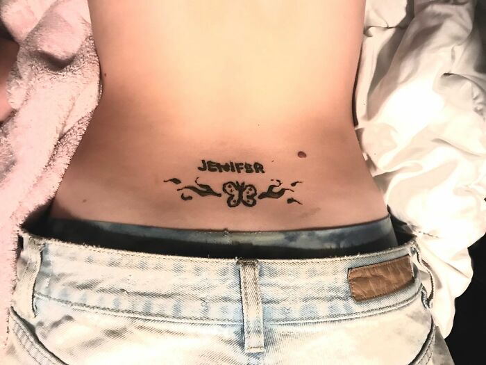 Lower back tattoo with the name "Jenifer" and butterfly design.