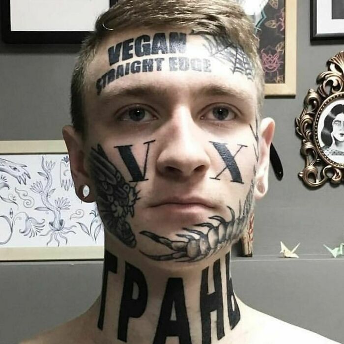 Person with multiple face and neck tattoos displaying various designs and words, a questionable tattoo choice.