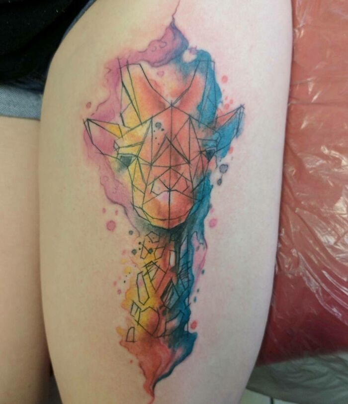 Geometric tattoo of a giraffe head with watercolor effect on skin.