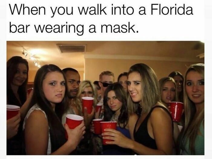 People in a Florida bar giving strange looks at someone wearing a mask, highlighting typical "Florida Man" humor.