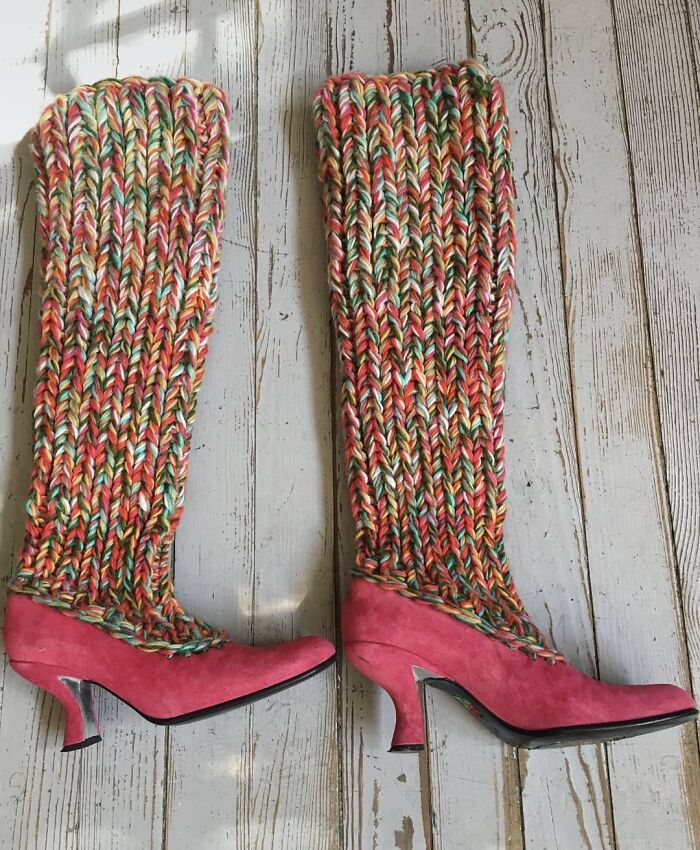 Colorful knitted leg warmers attached to pink high-heeled shoes, showcasing weird shoes on a wooden floor.