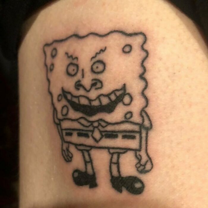 Horrible tattoo of a cartoon character with a distorted face and exaggerated features on a person's skin.