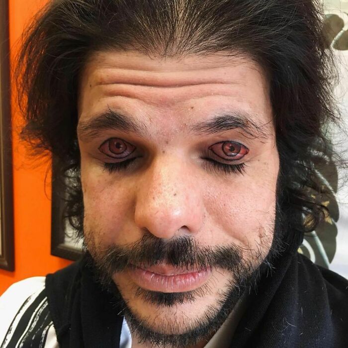 Man with unusual tattooed eyelids resembling red eyes, highlighting a tattoo fail.