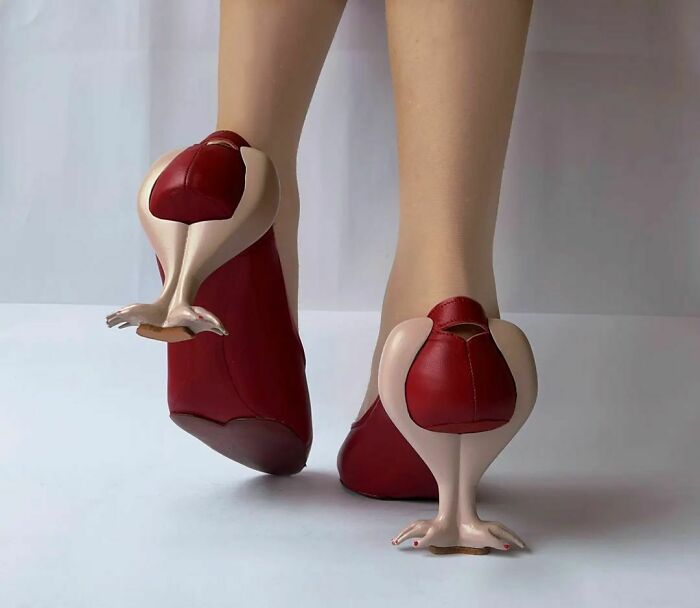 Woman wearing weird shoes with bird leg heels in red.