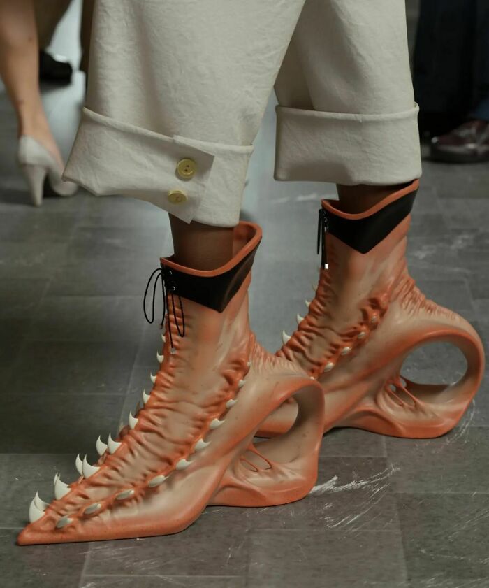 Weird shoes with claw-like design and unique heels worn with white pants buttoned up at the cuff.