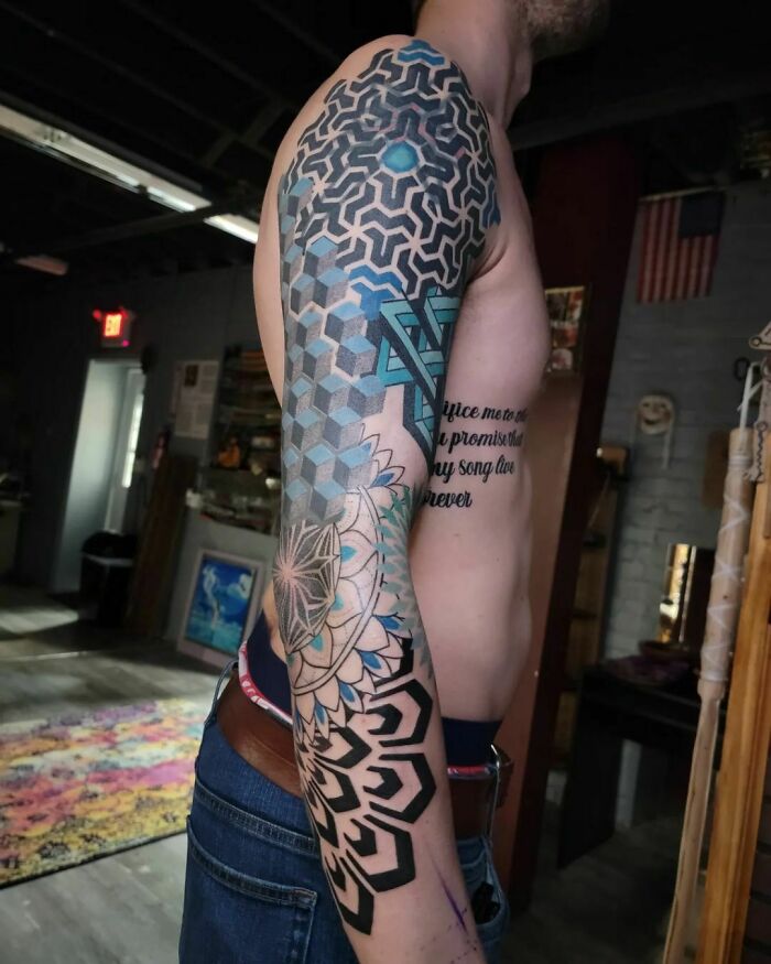 Arm tattoo with intricate geometric designs in blue and black, showcasing creative geometric tattoo artistry.