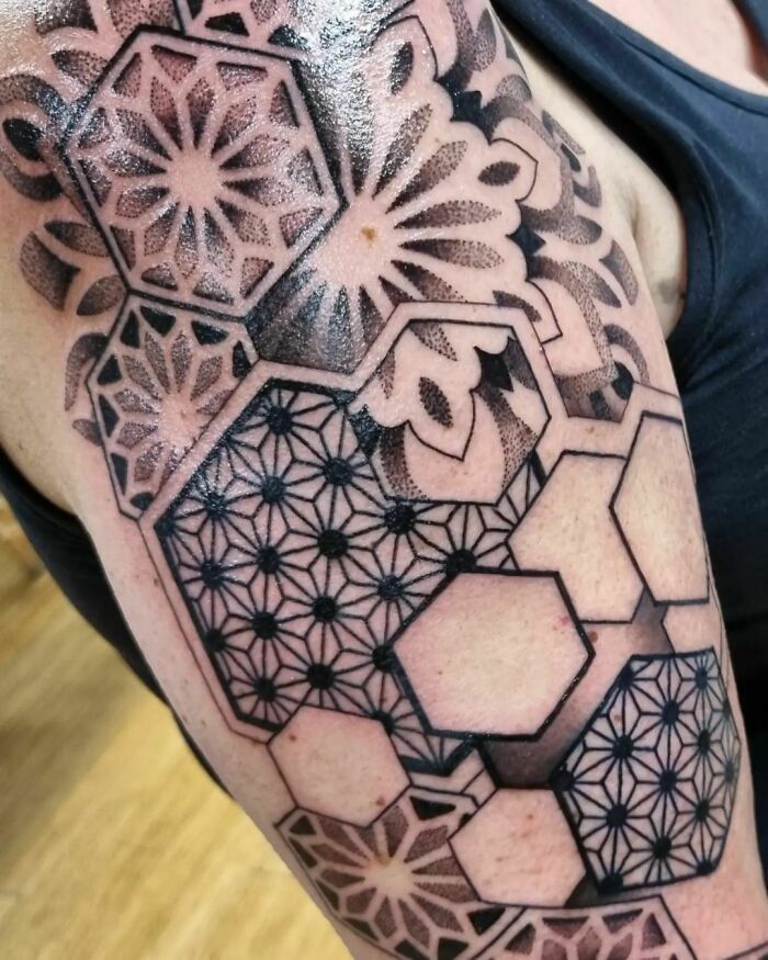 Geometric tattoo featuring intricate shapes and forms on an arm, showcasing creative design elements.