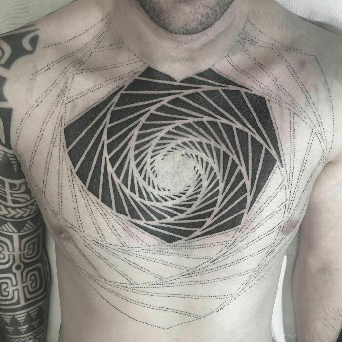 Geometric tattoo design on chest, featuring intricate shapes and forms in a spiral pattern, showcasing creativity.