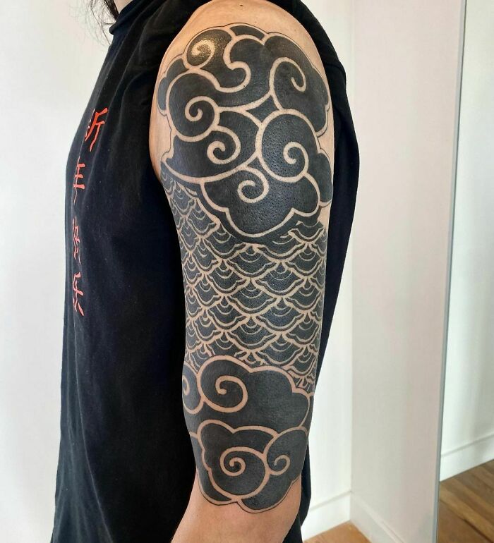 Arm with intricate geometric tattoo designs featuring swirling and wave-like patterns, showcasing creativity.