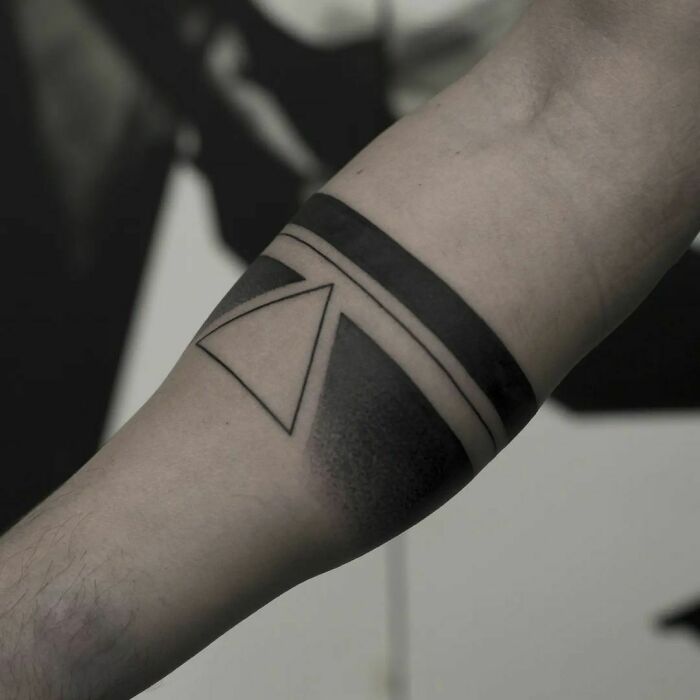 Geometric tattoo design on forearm, featuring a triangle and bold black bands.