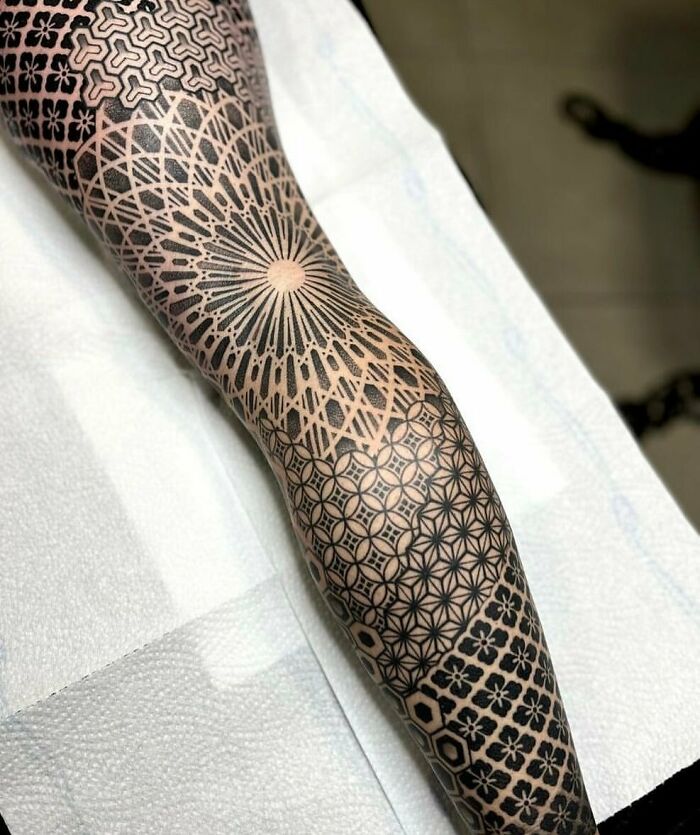 Geometric tattoo design showcasing intricate shapes and forms on a leg.