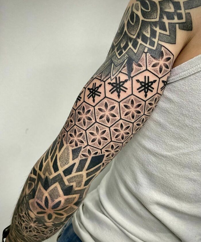 Arm with intricate geometric tattoo designs in black ink, highlighting creative patterns and modern tattoo ideas.