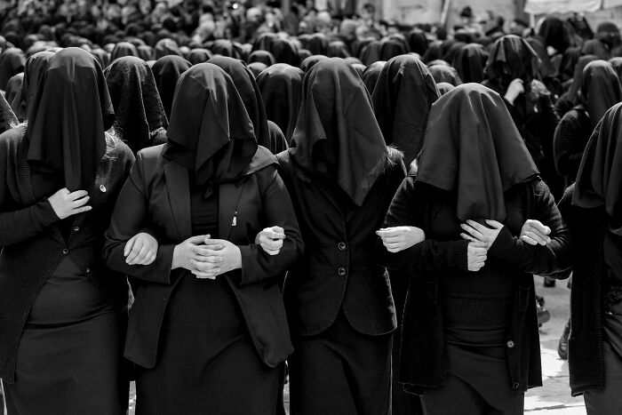 Group of women with covered faces standing arm in arm, symbolizing women and breaking stereotypes in a powerful moment.