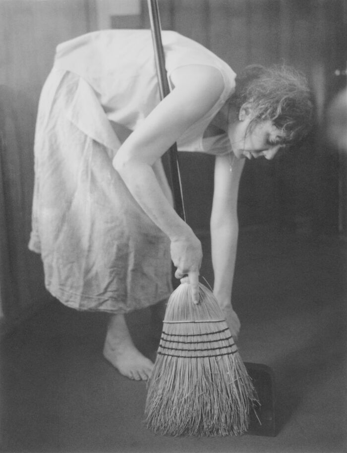 Woman breaking stereotypes by sweeping the floor barefoot in a simple dress, featured in AAP Magazine winning images.
