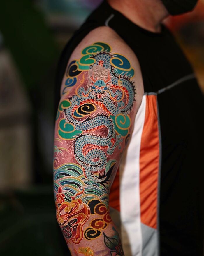 Colorful tattoo of a dragon on an arm, created by a Korean artist.