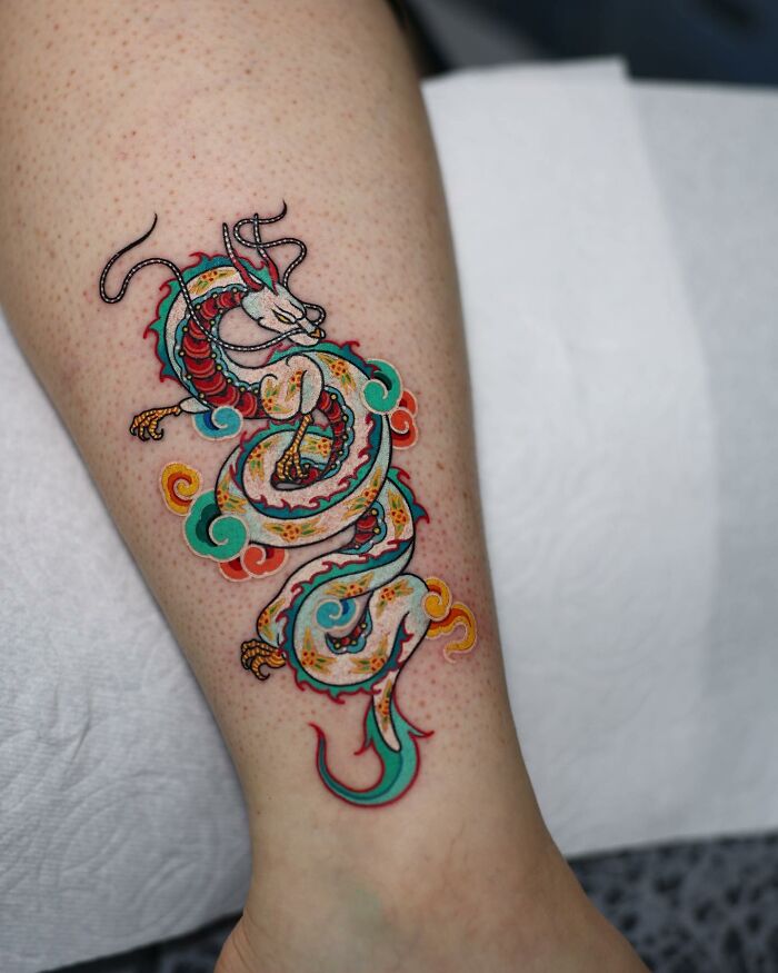 A mesmerizing dragon tattoo by a Korean artist, featuring vibrant colors and intricate details on a person's leg.