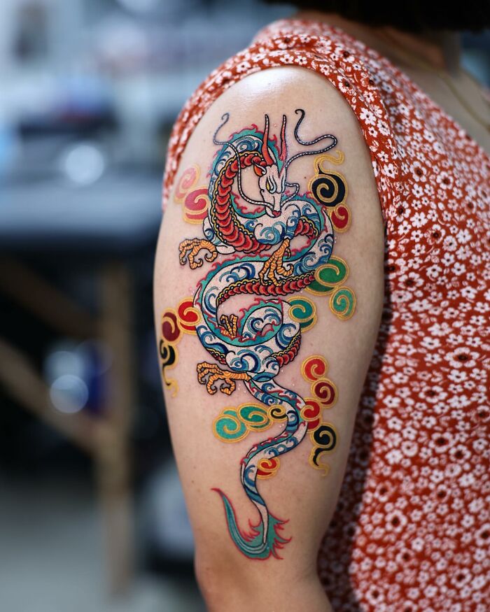 Colorful dragon tattoo on arm by a Korean artist, showcasing intricate and mesmerizing design.