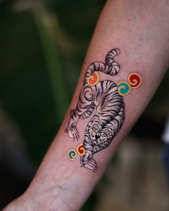 Korean artist's mesmerizing tattoo of a tiger on an arm, featuring vibrant colors and intricate patterns.