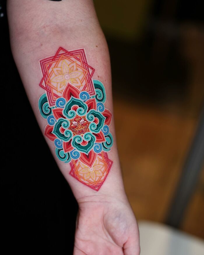 Colorful geometric tattoo design on arm, created by a Korean artist. Mesmerizing patterns in vibrant hues.
