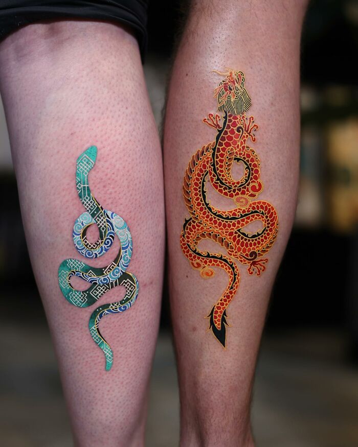 Two colorful snake tattoos on legs, showcasing mesmerizing designs by a Korean artist.