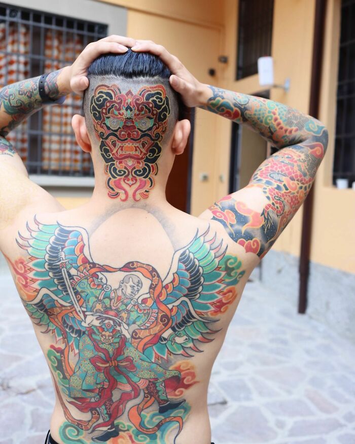 Colorful Korean tattoo art covering a person's back, featuring intricate designs and vibrant colors.