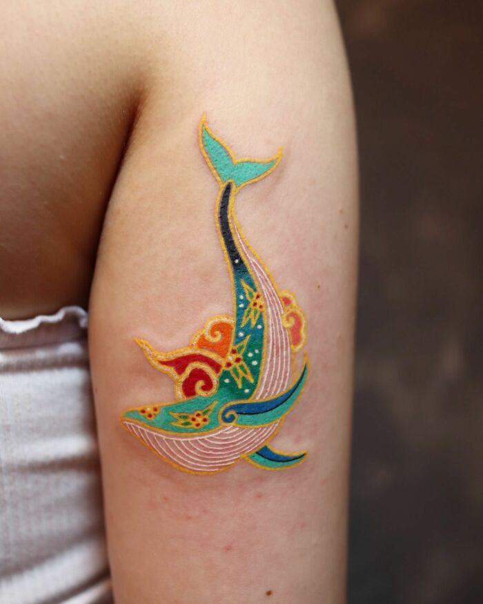 Colorful whale tattoo by Korean artist, featuring intricate patterns on an arm. Mesmerizing tattoos in vibrant hues.