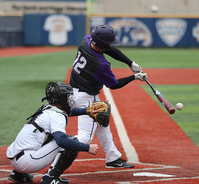 Person hits the ball in a baseball field 