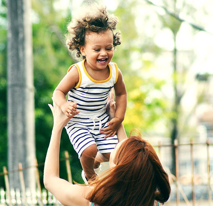 Woman throwing her kid in the sky