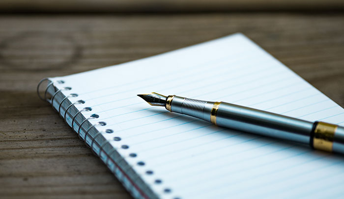 A pen and paper on a wooden table 
