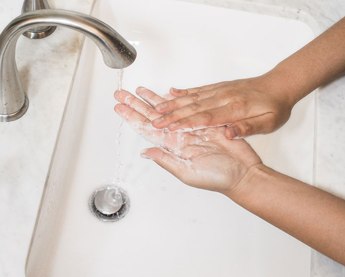 Person washing his hands under a tap with soap 