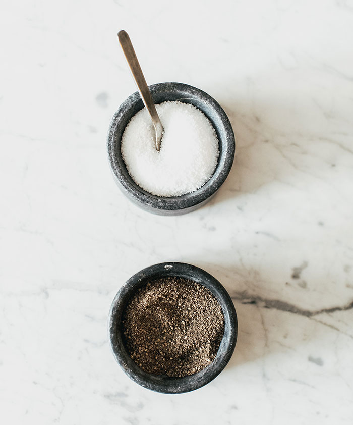 Salt and pepper in grey containers on table 