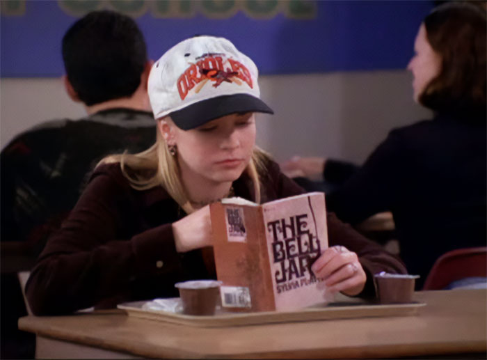 Sabrina eating and reading a book in the school canteen