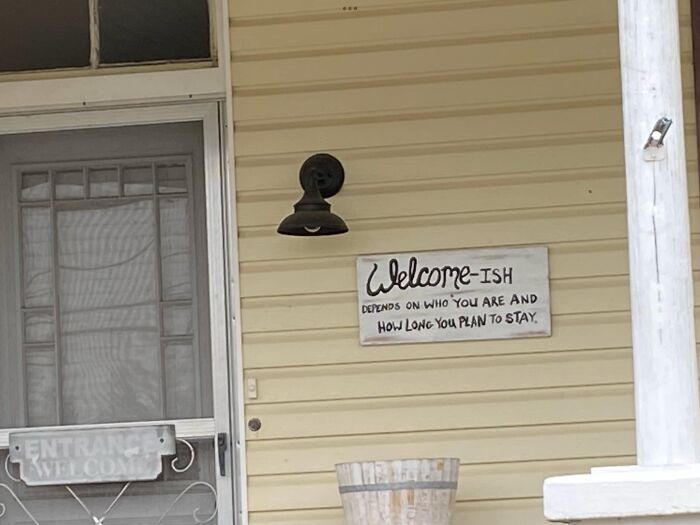 Humorous absurd sign on porch reading welcome-ish, highlighting hilariously absurd signs shared in online group.