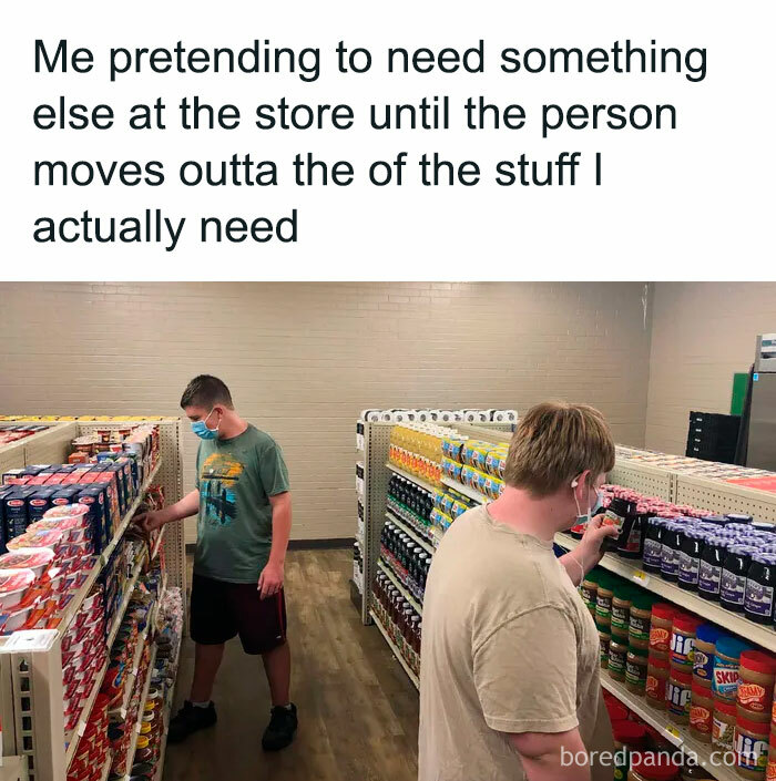 Two people wearing masks in a grocery store aisle, illustrating an introvert meme about avoiding social interaction.