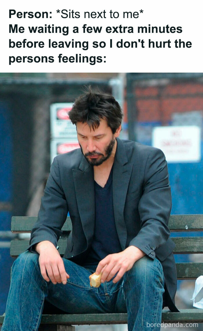 Man in a blazer sitting alone on a bench, representing introvert feelings in a meme about social discomfort.