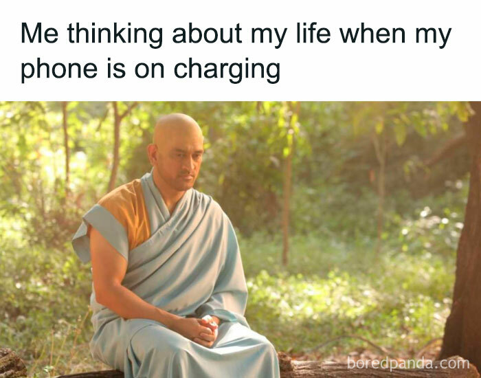 Man in traditional robes sitting quietly outside, reflecting with a phone on charging, introvert friends meme concept.