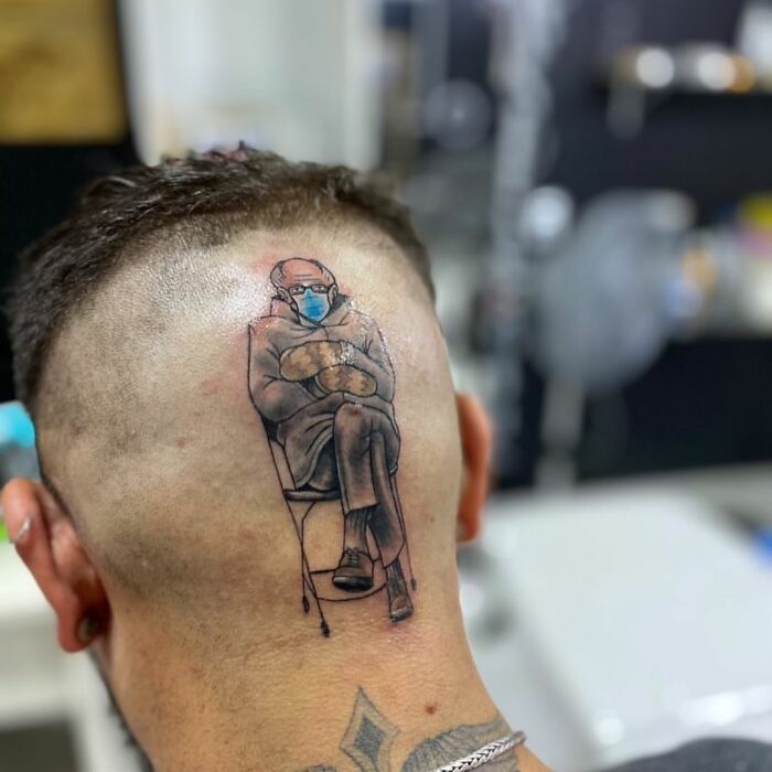 Unique tattoo of a masked, seated figure on the back of a person's head, showcasing a creative tattoo choice.