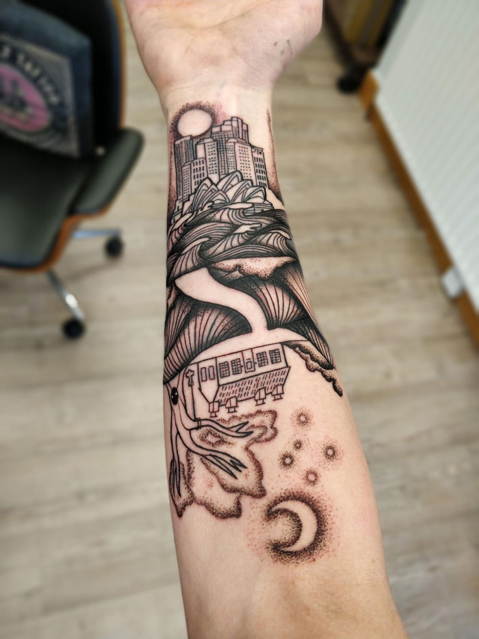 Geometric tattoo on forearm depicting cityscape, waves, and celestial elements in intricate black ink design.