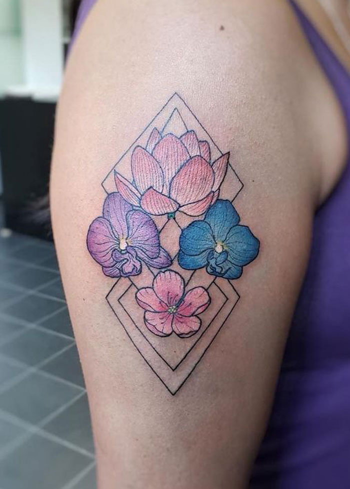 Geometric tattoo of colorful flowers within diamond shapes on upper arm.